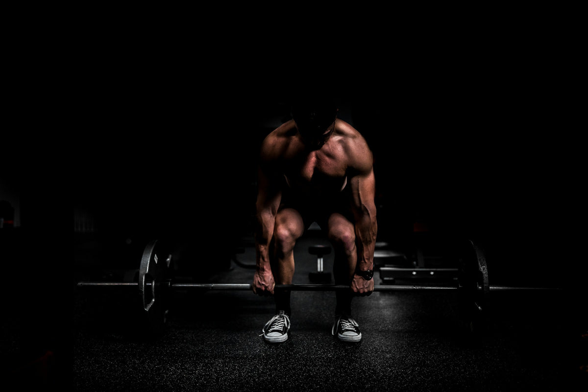 Athlete setting up a deadlift in a dark gym